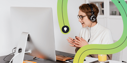 A customer service agents take a call in front of a computer at her desk.